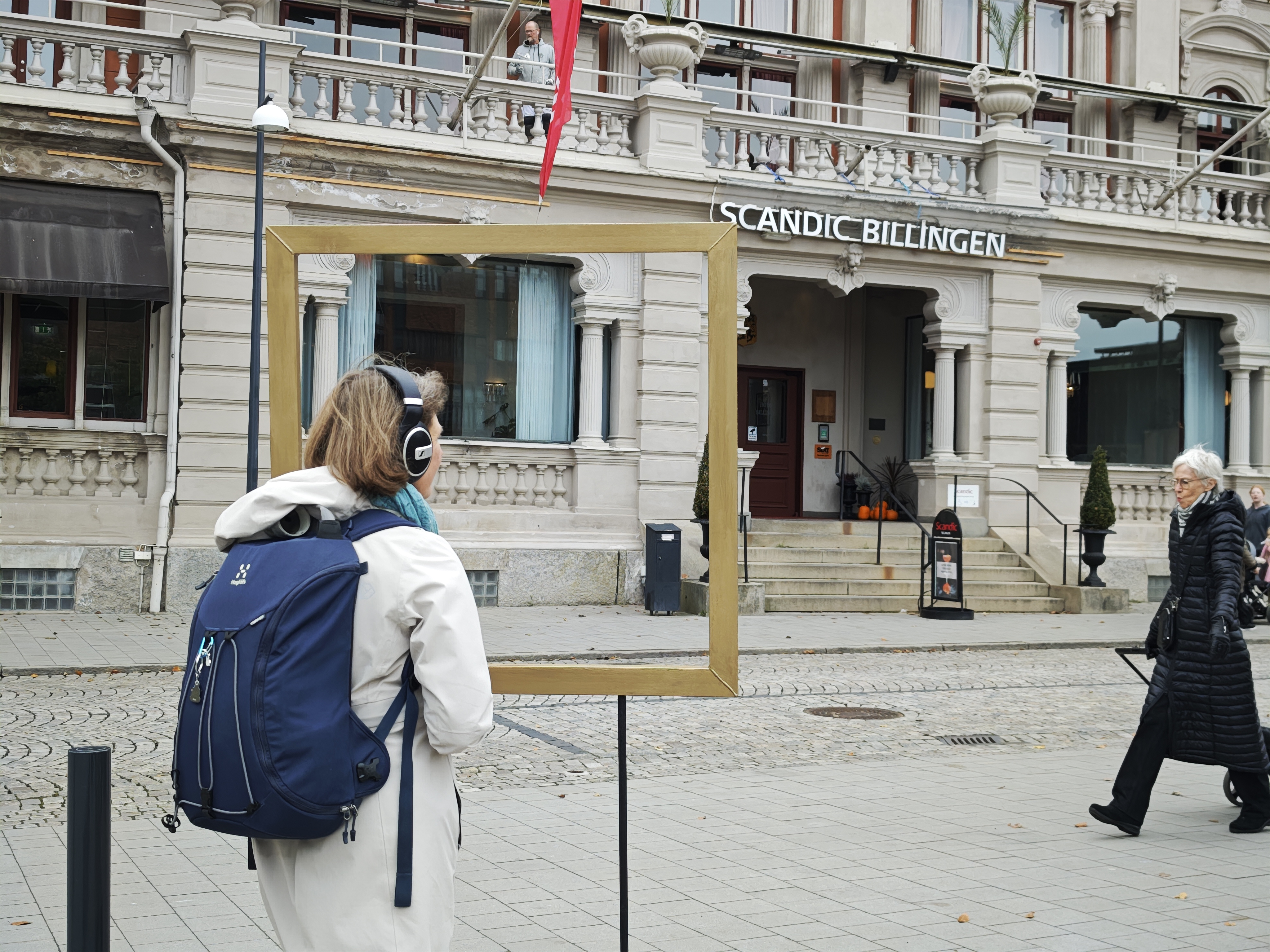Participant listening in front of a frame facing Hotel Billingen